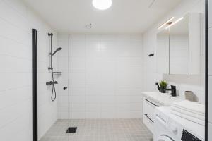 a white bathroom with a shower and a sink at Tuusulan Olympiatalo in Hyrylä