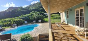 a house with a swimming pool with mountains in the background at Santosha Barbados in Saint Andrew