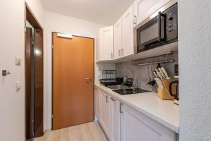 a kitchen with white cabinets and a microwave at Peak Moments - by myNests in Aich