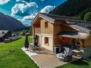 een hut met een terras met een televisie en een parasol bij Alpen Chalet in Morzine