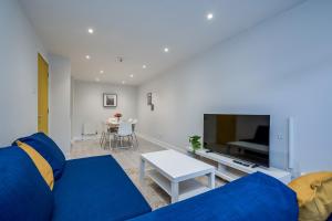 Una sala de estar con un sofá azul y una mesa. en Belfast City apartment with free parking!, en Belfast