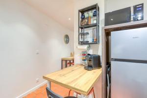 Una pequeña cocina con una mesa y un refrigerador. en La Reine, en Béziers