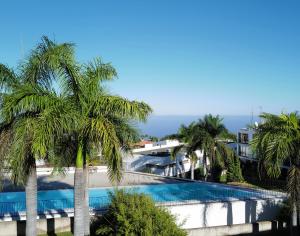 a pool with palm trees in front of a building at FEEL GOOD Ferienapartment mit Meerblick und Pool in Santa Úrsula