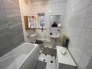 a white bathroom with a tub and a sink at Single room 10 minutes to Central London in London