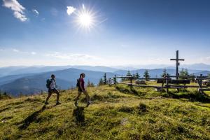two people walking on a hill with a cross in the background at Appartement Cseho in Murau