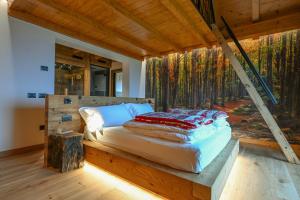 a bed in a room with a wall of trees at Cinque Sensi Wellness Apartments in Braz