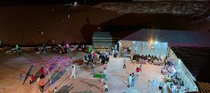 a group of people standing around a stage at night at blueskyrum. in Wadi Rum +32 photos