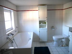 a white bathroom with a tub and a toilet at Ferienwohnung unter Reet in Risum-Lindholm