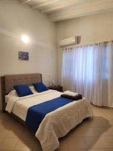 Casa turística contemporánea في بوكارامانغا: غرفة نوم بسرير وملاءات زرقاء ونافذة