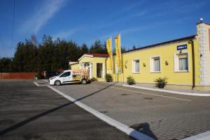 a yellow building with a car parked in a parking lot at Noclegi Kochlice in Kochlice