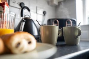 two coffee cups on a counter with a plate of food at Stunning Cardiff Wharf View 4 Bed Free Parking in Cardiff
