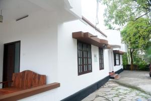 a white building with a bench on the side of it at Crystal Palace Odayam in Varkala