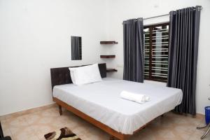 a bedroom with a bed with white sheets and a window at Crystal Palace Odayam in Varkala