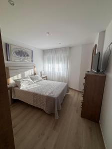 ein Schlafzimmer mit einem Bett und einem Flachbildfernseher in der Unterkunft Piso en Ribeira a 20metros de la playa de Coroso by Cristian&Tamara "alquileres" in Ribeira