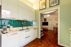 a kitchen with white cabinets and green walls at Cairoli Suite e Garage in Milan