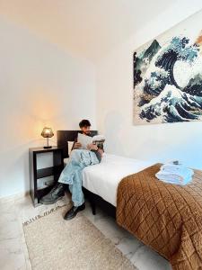 a woman sitting on a bed with a laptop at Gardens Guest House in São Vicente