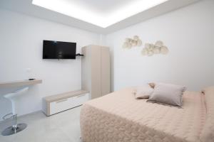 ein weißes Schlafzimmer mit Bett und Flachbildfernseher in der Unterkunft Residence BLANCO GARDEN 1 a 100 mt dalla spiaggia di Posto Vecchio Marina di Pescoluse in Marina di Pescoluse