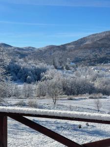 a snowy field with a fence and mountains in the background at Holiday Home Zagorka in Ogulin