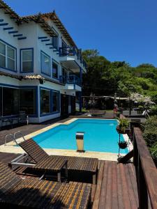 a swimming pool with lounge chairs and a house at Top de Buzios Boutique Hotel & Spa in Búzios