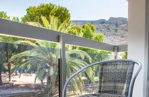 a chair on a balcony with a view of a palm tree at Anemos Rooms & Apartments in Nafplio