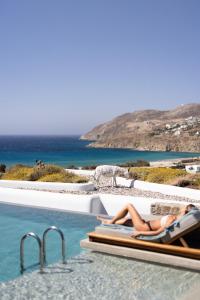 Una mujer recostada en una silla junto a una piscina. en Mileo, en Playa Kalo Livadi