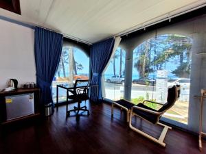 a living room with blue drapes and chairs at Solstice Phuket in Nai Thon Beach