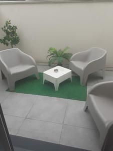 two white chairs and a table on a green rug at Love Room Sensuelle in Tremblay En France