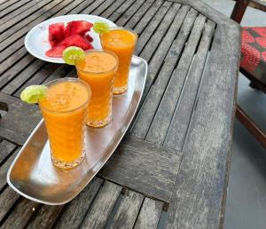 a tray with four drinks and a plate of fruit at Arijaana Guesthouse in Gunjur
