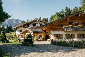 a large wooden house in the mountains with a yard at Berghotel Schlossanger Alp in Pfronten