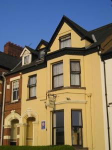 a yellow house with a black roof at Abbey Guest House in Norwich