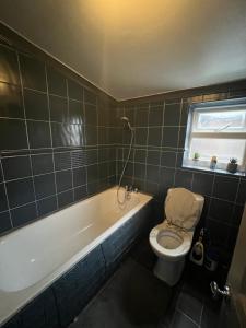 Un baño con bañera, inodoro y ventana. en room near Luton center, en Luton