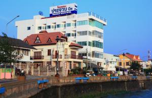 a building with a sign on top of it next to a river at Prachuap Beach Hotel in Prachuap Khiri Khan
