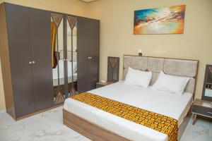 - une chambre avec un grand lit blanc et une armoire dans l'établissement StayAfrica, à Ouagadougou