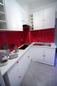 kuchnia z białymi szafkami i czerwonymi płytkami w obiekcie Riquewihr w mieście Riquewihr