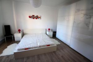 een witte slaapkamer met een bed en twee nachtkastjes bij Riquewihr in Riquewihr