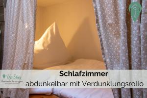 a bedroom with a bed and curtains with the words schitzler mitt ver at Butzenhuuske in Krummhörn