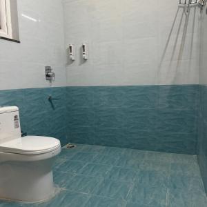 a bathroom with a toilet and a green tiled floor at Panorama Villa at Hartola by Kusumith Retreats in Rāmgarh