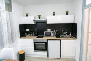a kitchen with white cabinets and a microwave at Joli studio Clim & Wifi in Pithiviers