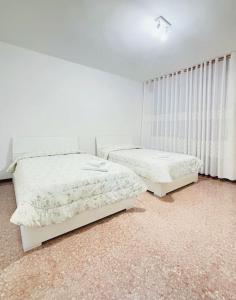 two beds in a bedroom with white walls at Casablanca in Venice +2 photos