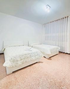 two beds in a room with white walls at Casablanca in Venice