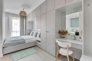 a bedroom with a bed and a chair and a mirror at Scala Apartamenty by Moderna Profit- Łąkowa 60C in Gdańsk +111 photos