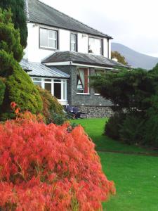 una casa con flores rojas delante de un patio en Lake District Castle Inn, en Keswick