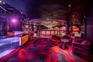 a room with a bar with red chairs and a stage at Glee Nairobi in Nairobi +109 photos