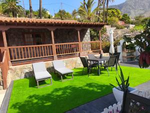 un patio con una mesa y sillas sobre césped verde en La Finca De Victoria Alojera, en Vallehermoso