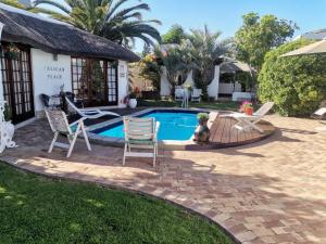 ein Swimmingpool mit zwei Stühlen und einem Haus in der Unterkunft Pelican Place Guest Cottages in Durbanville