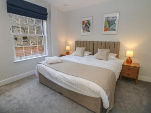 a bedroom with a large bed and two windows at 2 Rock Mill Holiday Apartments in Eyam
