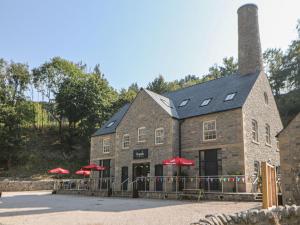 a building with red umbrellas in front of it at 2 Rock Mill Holiday Apartments in Eyam