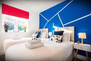 zwei Betten in einem Zimmer mit blauen und roten Wänden in der Unterkunft Hatfield Haven - Modern 2-Bed Retreat near Uni, Business Park & City Center, FREE Parking, Big savings on Longer Stays in Hatfield + 34 Fotos