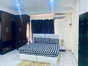 a bedroom with a bed with a black and white comforter at Opal Exquisite Apartment in Lekki