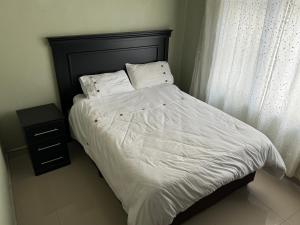 ein Bett mit schwarzem Kopfteil und weißen Laken und Kissen in der Unterkunft Feel At Home Away From Home in Durban